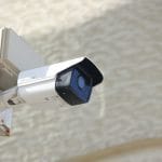 Hikvision security camera mounted on a wall, one of thousands still vulnerable to command injection flaw